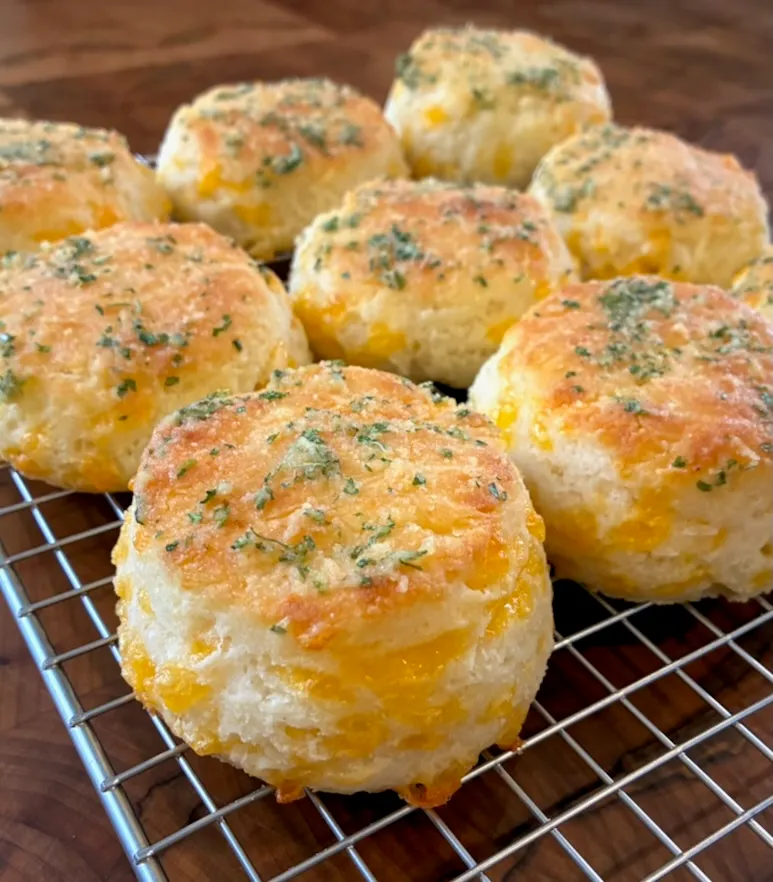 A cooling rack full of cheesey golden brown flaky gluten-free biscuits