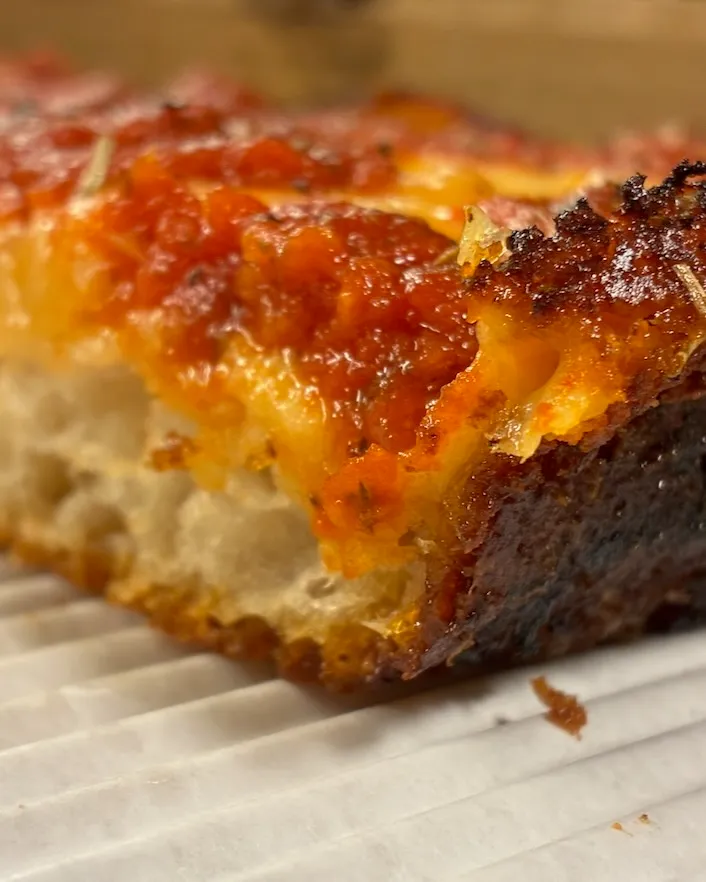 Saucy cheesy crispy edges Detroit-style pizza slice