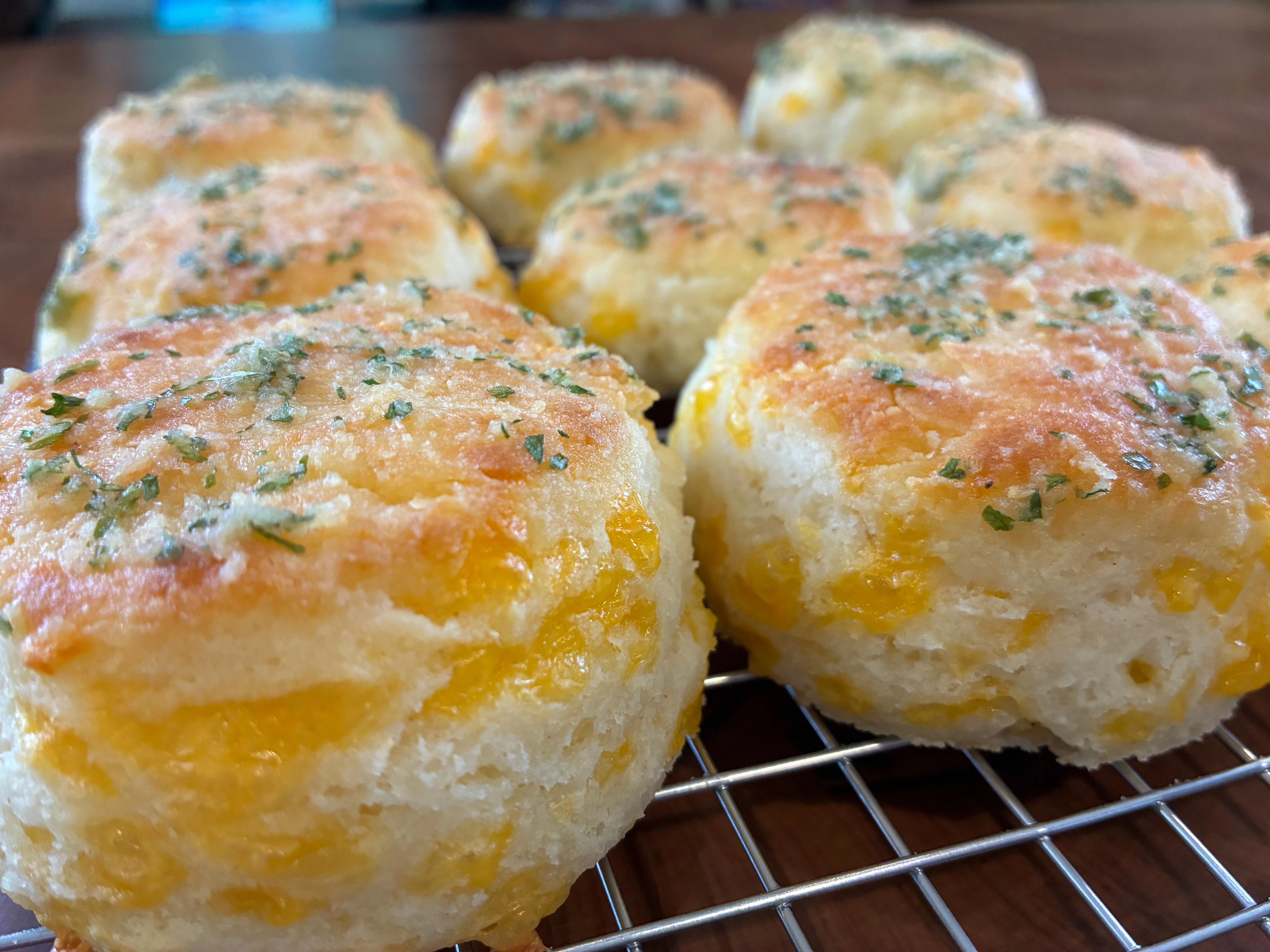 A cooling rack full of cheesey golden brown flaky gluten-free biscuits